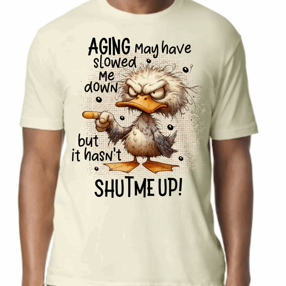 Off white T-shirt with a grumpy cartoon duck pointing and text that reads: “Aging may have slowed me down but it hasn’t shut me up.”