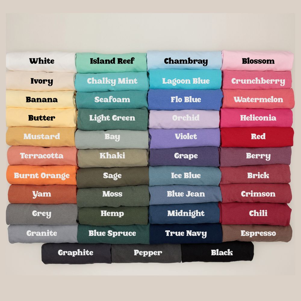 “Comfort Colors t-shirt color chart showing stacked rolled tees in shades like Crunchberry, Lagoon Blue, Banana, Orchid, Terracotta, Blue Jean, and more. Each color name is printed directly on the shirt for easy selection.”