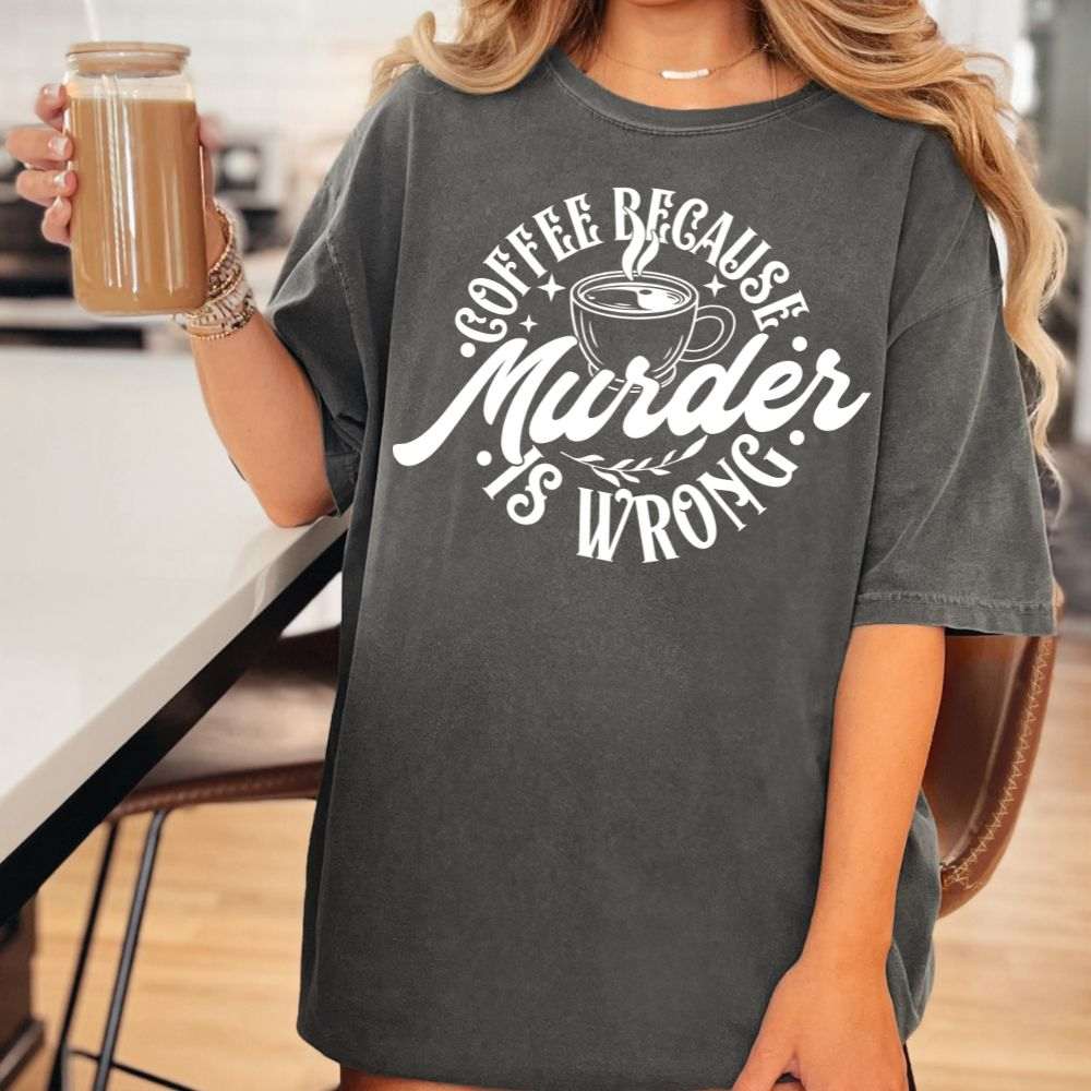 Woman wearing a charcoal gray t-shirt with “Coffee Because Murder Is Wrong” in bold white text and coffee cup graphic.