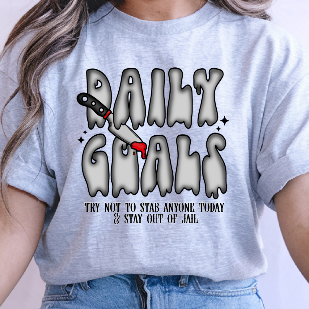 Gildan Softstyle Sport Grey graphic T-shirt featuring Daily Goals, a dripping knife, and Try Not to Stab Anyone Today wording.