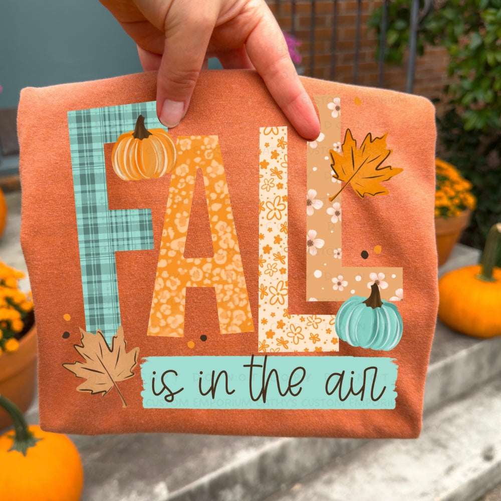 Fall Is in the Air graphic T-shirt with colorful pumpkins and autumn leaves on a Heather Autumn shirt.