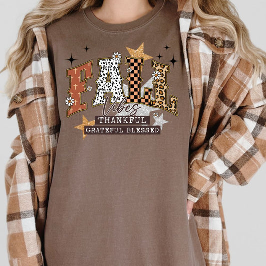 Person wearing a brown shirt with 'Fall Vibes Thankful Grateful Blessed' text and decorative letters.
