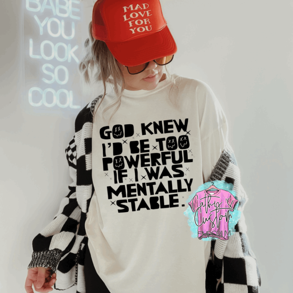 Off White graphic T-shirt with bold black text that reads "God knew I’d be too powerful if I was mentally stable." Styled with a checkered cardigan and red cap.