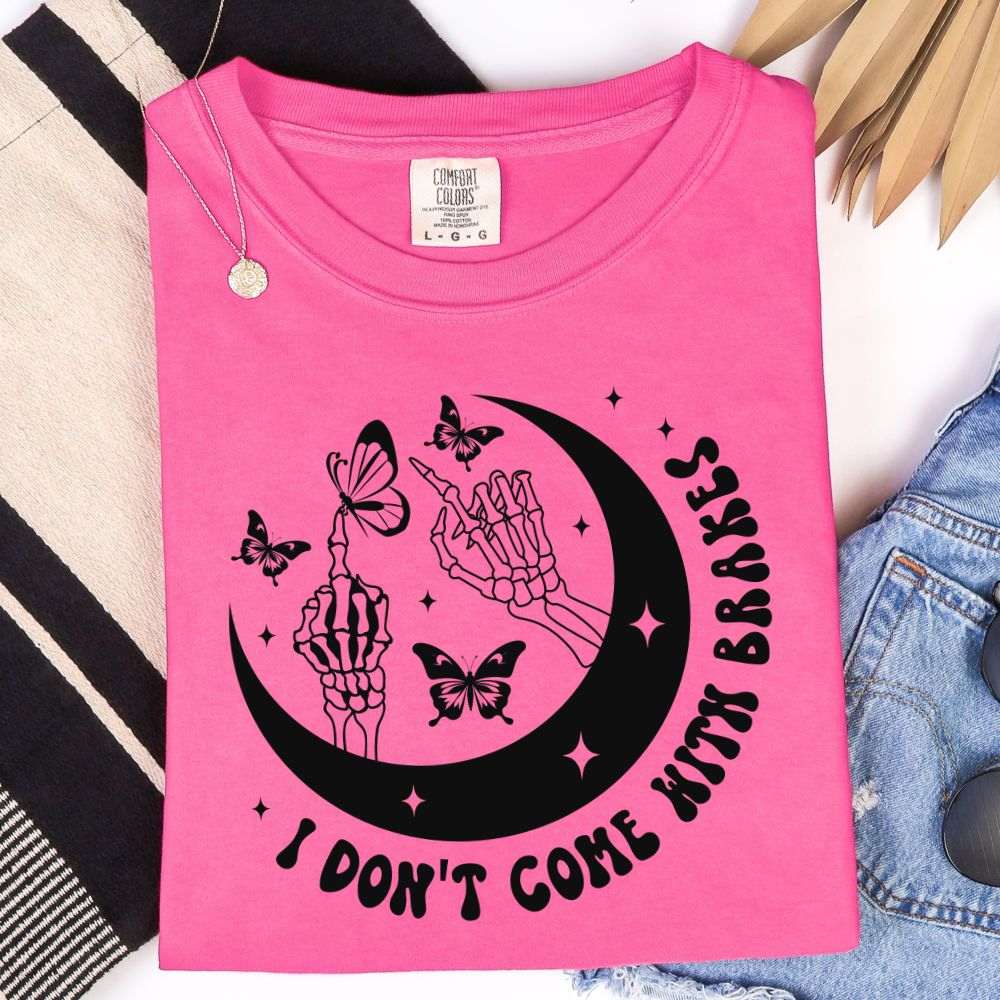 Watermelon pink t-shirt with black crescent moon, skeleton hands, butterflies, and “I Don’t Come With Brakes” text.