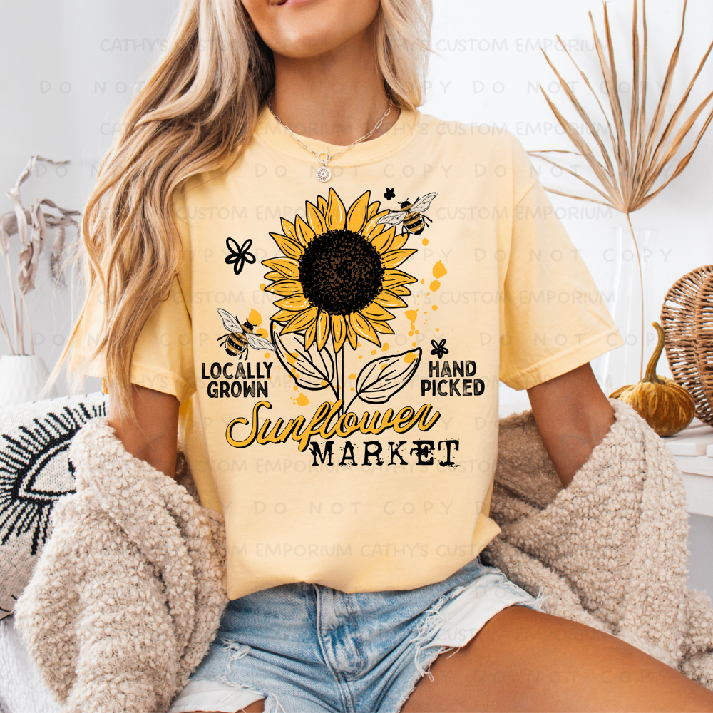 Locally Grown Sunflower Market graphic apparel shown on Comfort Colors Butter Daisy featuring a sunflower with bees.