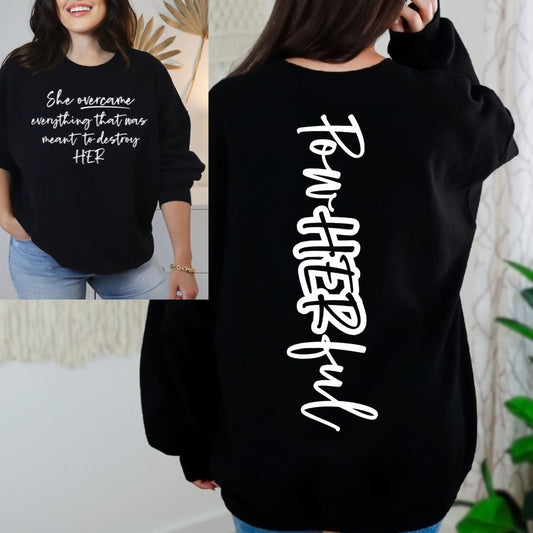 Black Gildan graphic sweatshirt with She Overcame quote on front and PowHERful text on back, empowering apparel for strong, confident women.