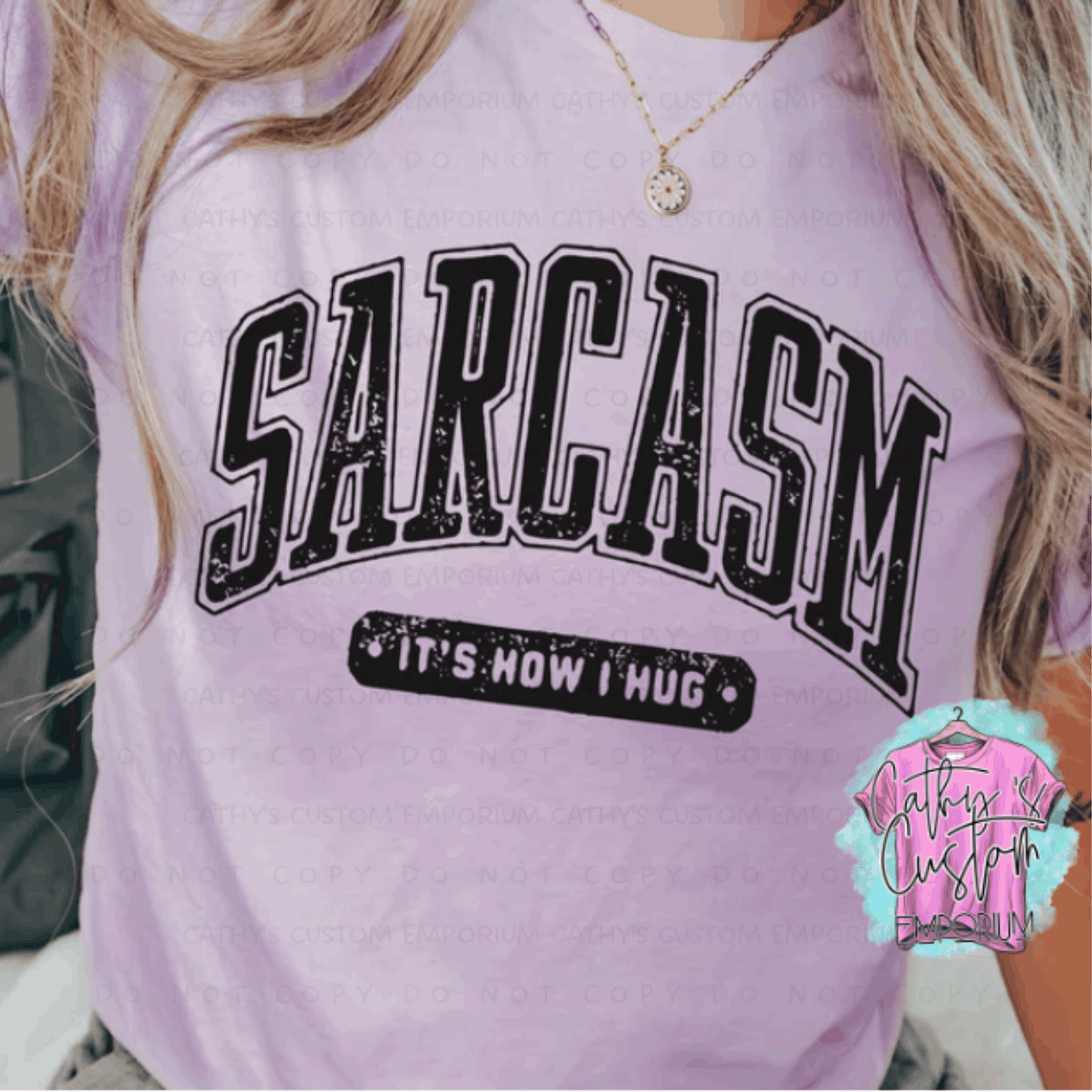 Pink Graphic T-shirt with "Sarcasm: It’s How I Hug" printed in bold, distressed varsity-style black font.
