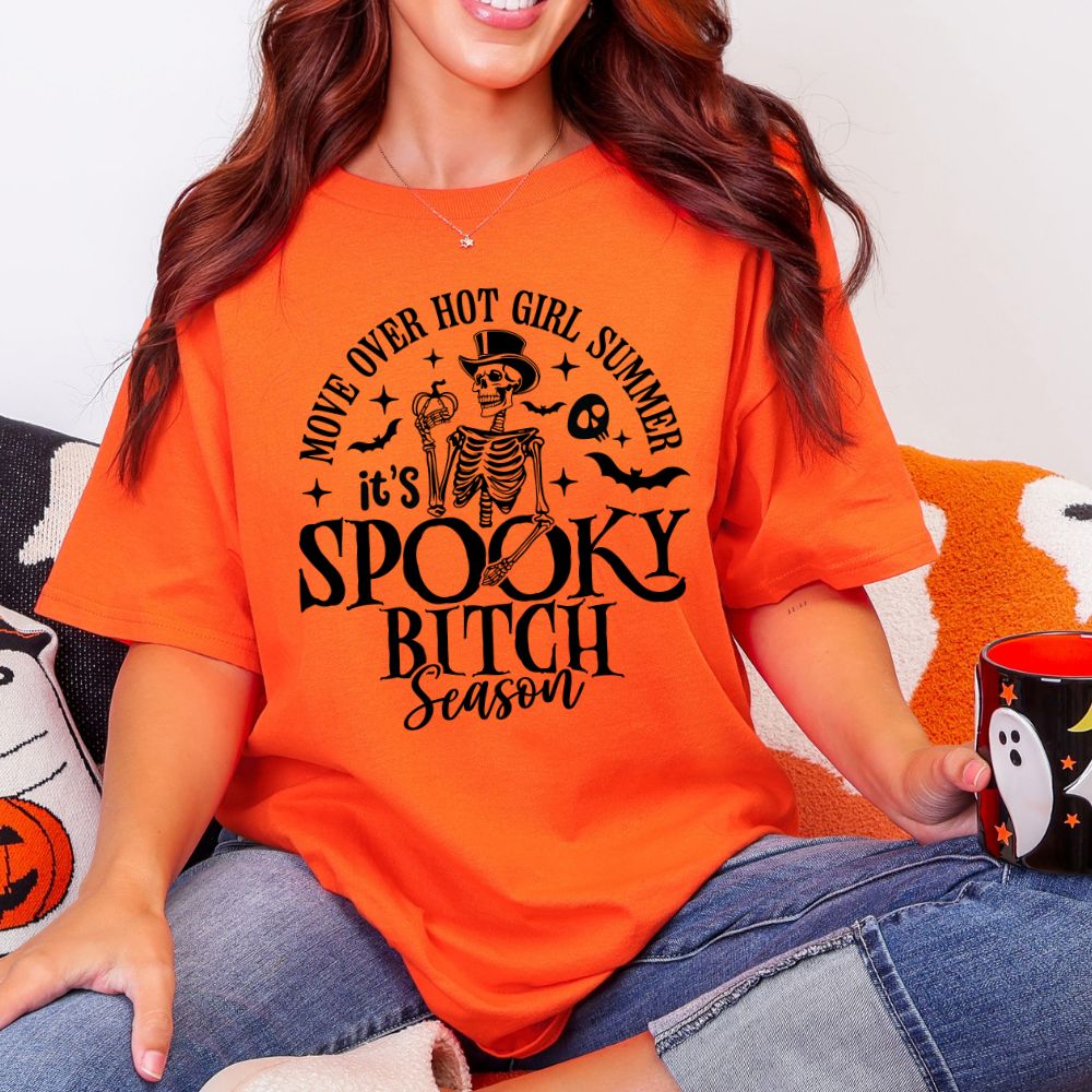 Person wearing an orange t-shirt with Halloween-themed text and graphics.