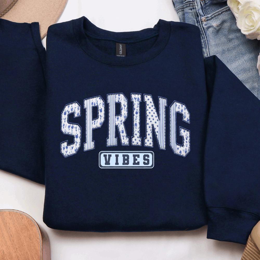 Navy graphic sweatshirt with blue and white varsity-style Spring Vibes design displayed in a flat lay