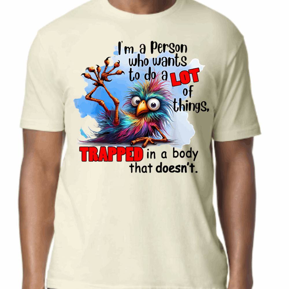 Off White T-shirt with a colorful cartoon creature and bold text that reads: “Trapped in a body that doesn’t.” Funny and relatable unisex tee.