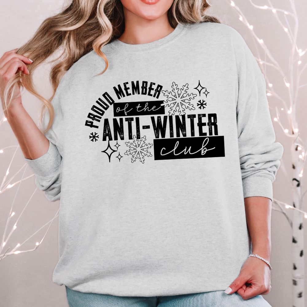 Person wearing a gray sweatshirt with 'Proud Member of the Anti-Winter Club' black text and snowflake design.