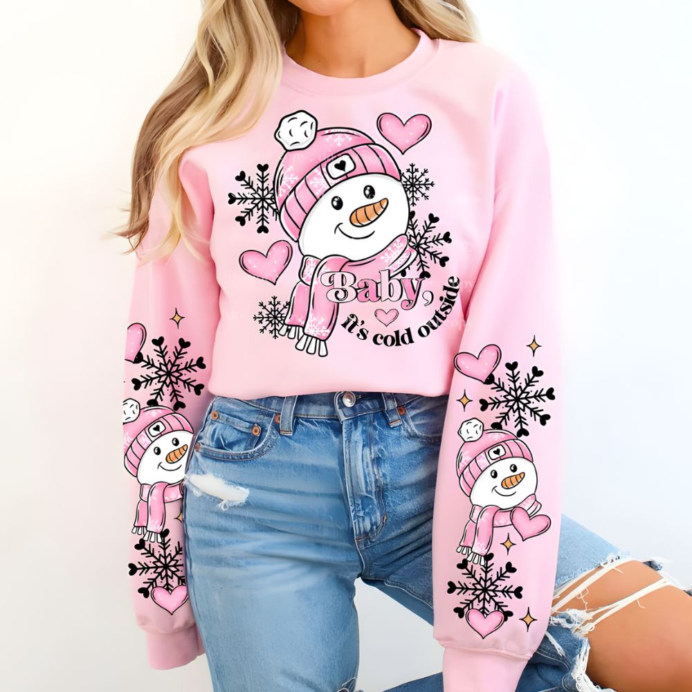 Person wearing a pink sweater with snowman graphics and text, paired with blue jeans.
