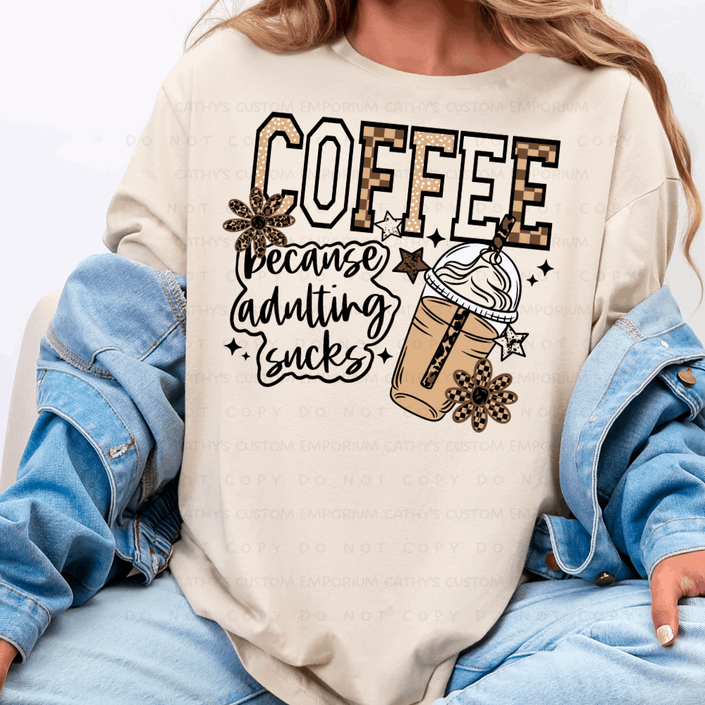 Coffee Because Adulting Sucks Graphic T-Shirt displayed on a Comfort Colors Ivory shirt.