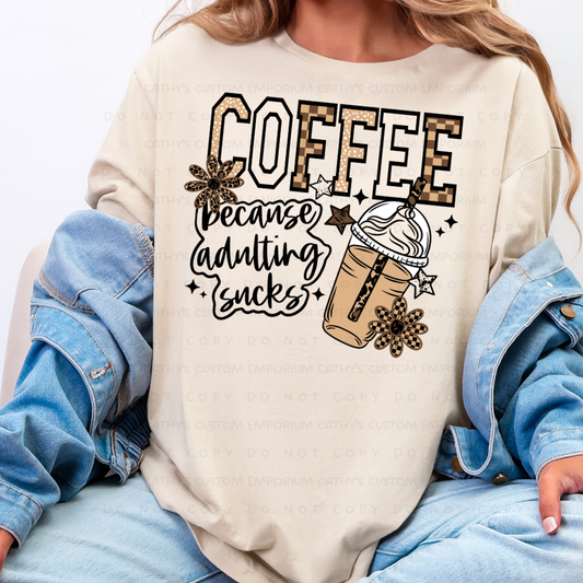 Coffee Because Adulting Sucks Graphic T-Shirt displayed on a Comfort Colors Ivory shirt.
