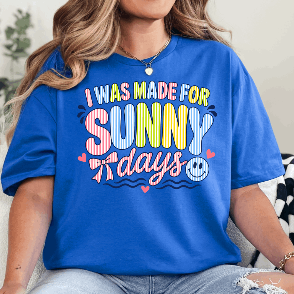 Person wearing a blue t-shirt with colorful text 'I was made for sunny days'.
