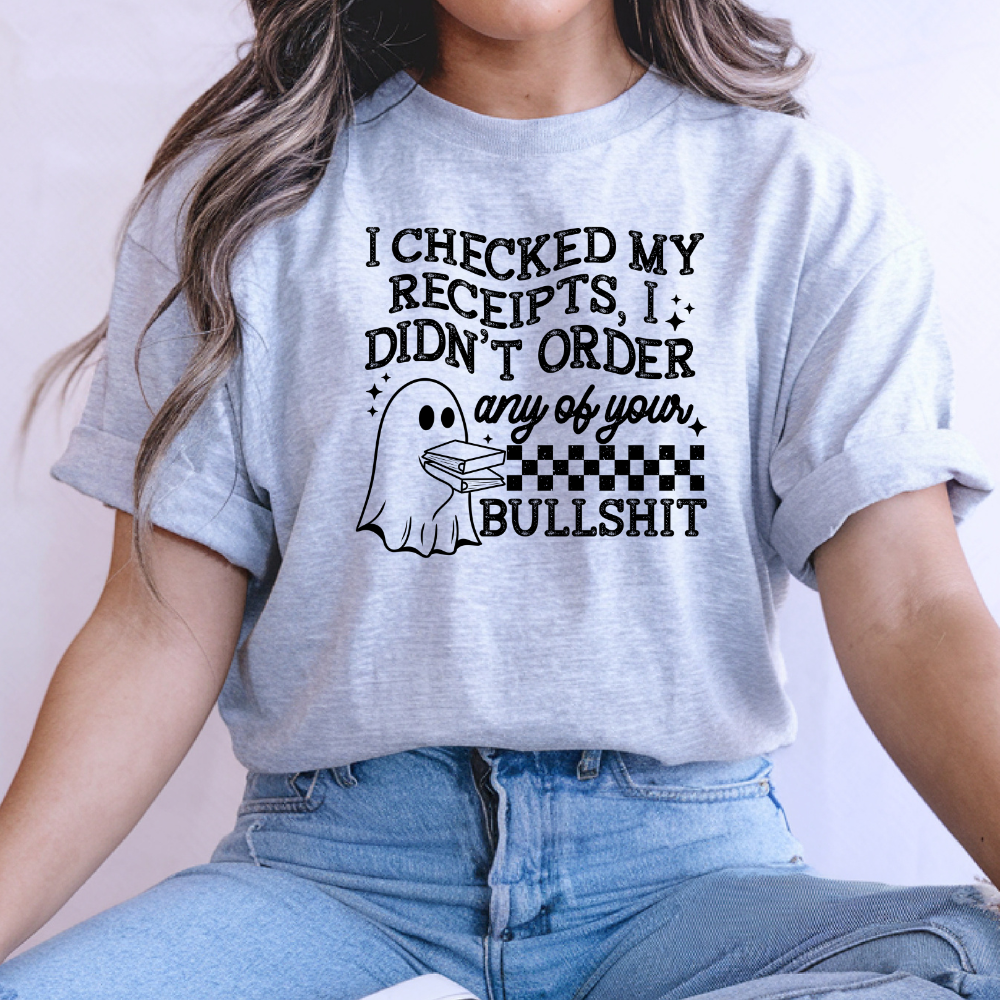 Woman wearing a light grey Graphic T-Shirt with a black I Checked My Receipts ghost design