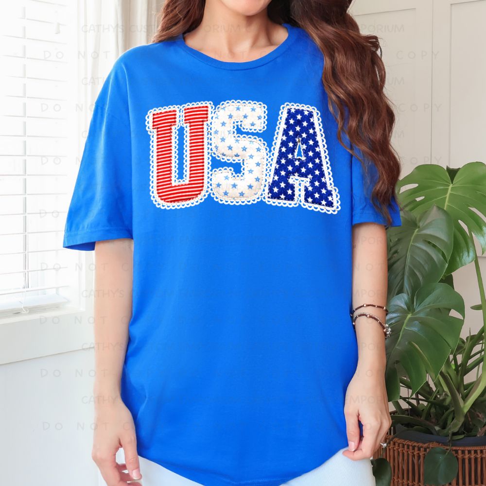 Blue patriotic graphic T-shirt with red white and blue USA lettering and lace-inspired details