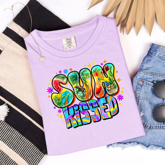 Orchid colored t-shirt with colorful “Sun Kissed” bubble letters filled with summer images.

