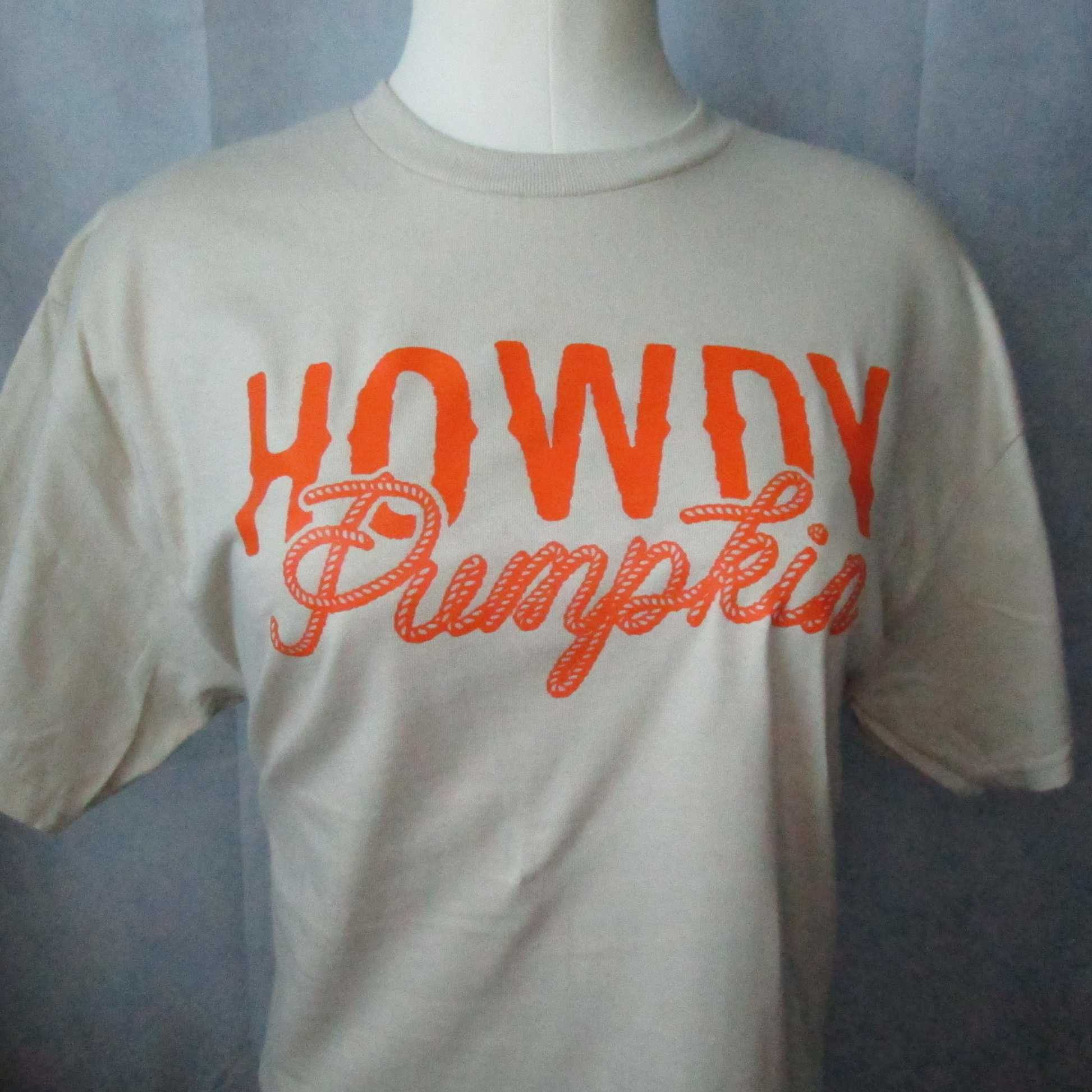 Bright orange ink on a sand colored t-shirt in a western theme. 