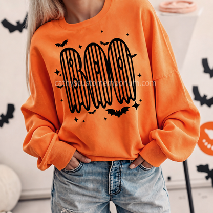 Woman wearing an orange BOO Halloween sweatshirt with black striped ghost lettering and bat accents