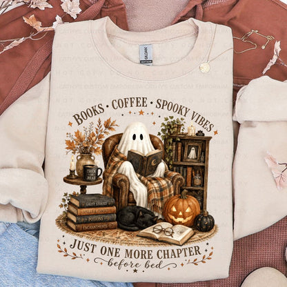 Light cream sweatshirt featuring a ghost reading in a cozy Halloween library scene with pumpkins, books, coffee, and the words Books Coffee Spooky Vibes and Just One More Chapter Before Bed.