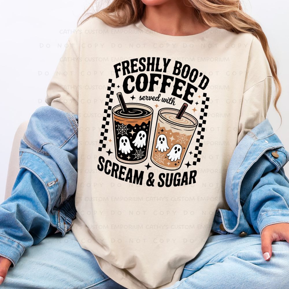 Cream sweatshirt featuring two ghost-covered coffee cups with checkerboard and star accents and the words Freshly Boo'd Coffee Served with Scream and Sugar.