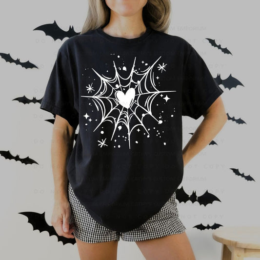 Black T-shirt with a white spiderweb graphic centered around a heart, surrounded by stars and paint-splatter accents.