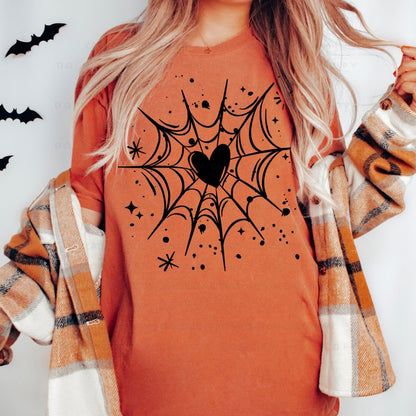 Rust-orange T-shirt with a black spiderweb graphic centered around a heart, surrounded by stars and paint-splatter accents.