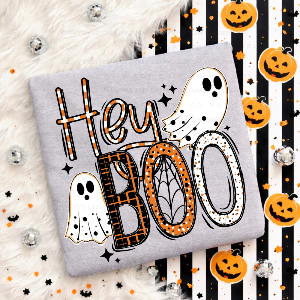 Gray folded sweatshirt with an orange, black, and white Hey Boo Halloween graphic featuring two ghosts, patterned lettering, and a spiderweb
