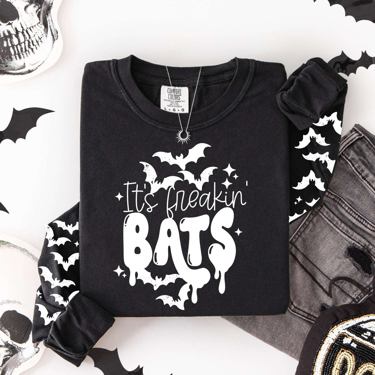 Flat lay of a black long-sleeve shirt featuring the words "It’s freakin’ BATS" with white bats and matching bat graphics down both sleeves.