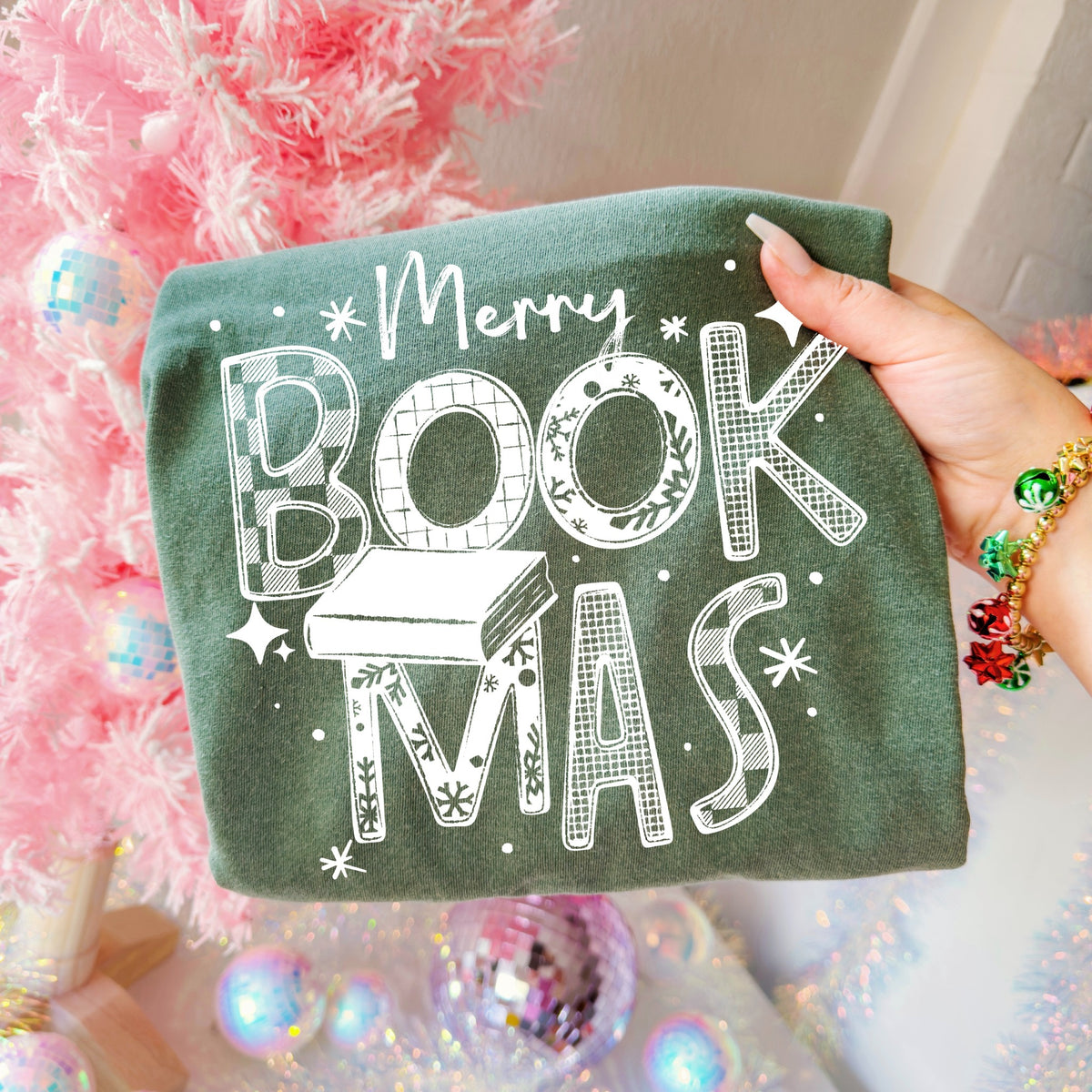 Merry Bookmas Christmas book lover graphic shirt design in white on a dark green garment