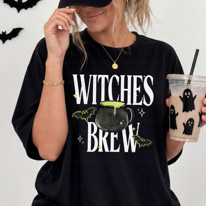 Woman wearing a black Witches Brew Halloween graphic shirt with a bubbling cauldron, bats, and lime green accents