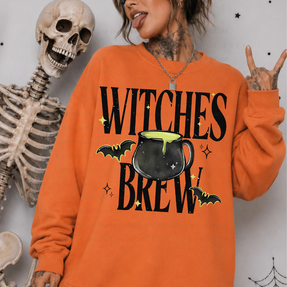 Woman wearing an orange Witches Brew Halloween sweatshirt with a black cauldron, bats, and lime green accents
