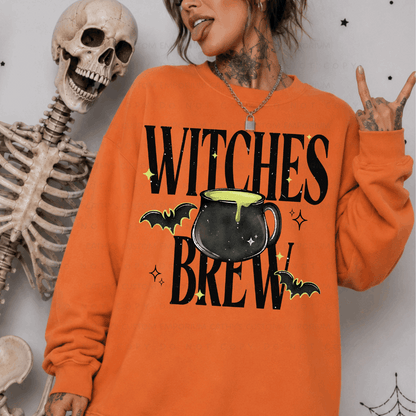 Woman wearing an orange Witches Brew Halloween sweatshirt with a black cauldron, bats, and lime green accents